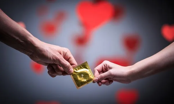 Two hands holding a condom